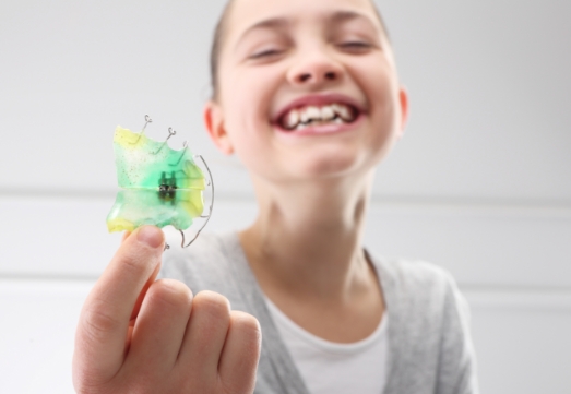Young girl holding an orthodontic appliance used for dentofacial orthopedics