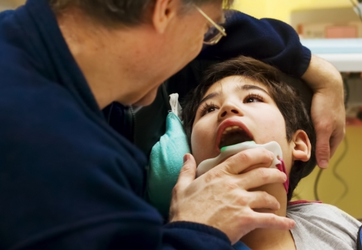 Dentist examining child's smile during special needs dental visit