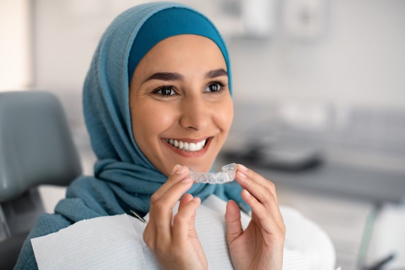 Patient smiling as they put in their clear aligners