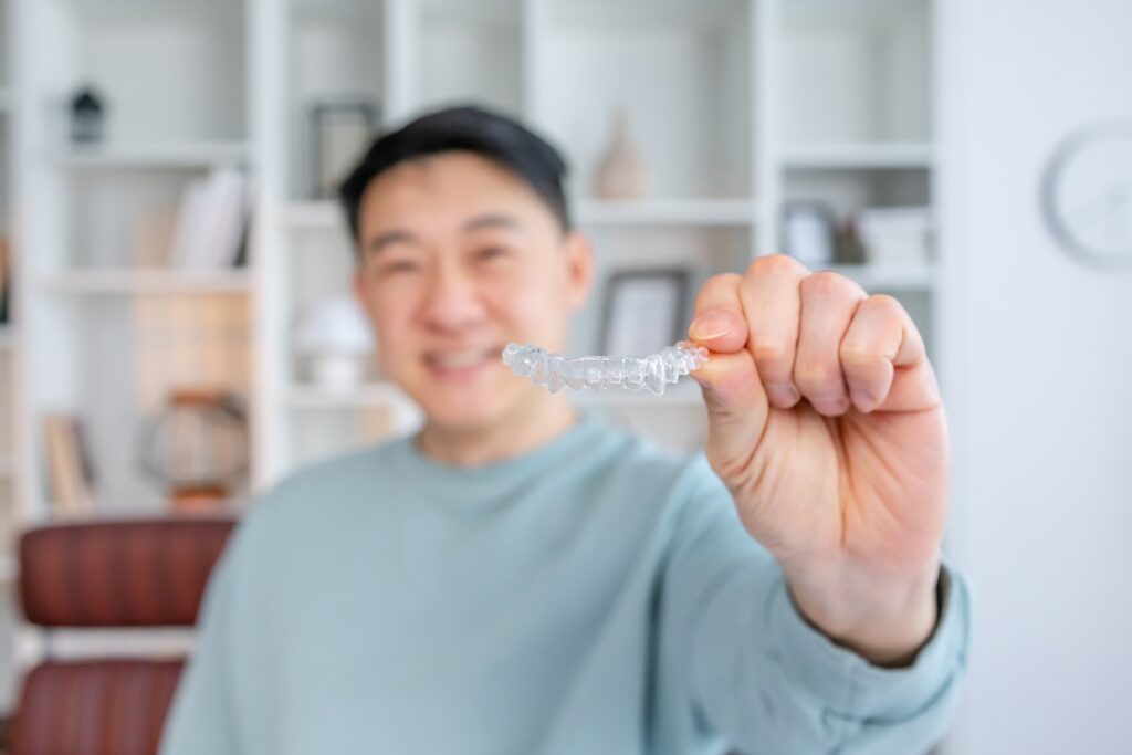Closeup of man smiling while holding clear aligner